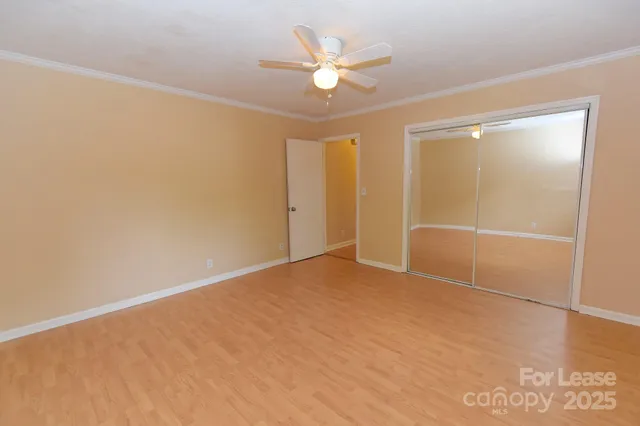 an empty room with closet and a ceiling fan