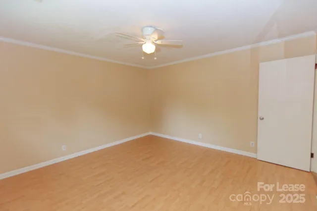 an empty room with a chandelier fan and windows