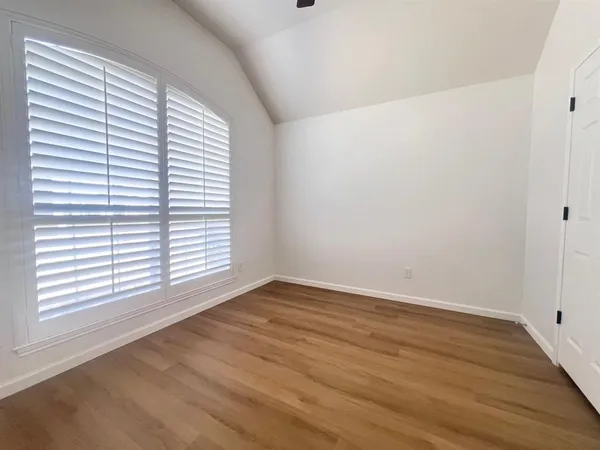 a view of an empty room and wooden floor and window