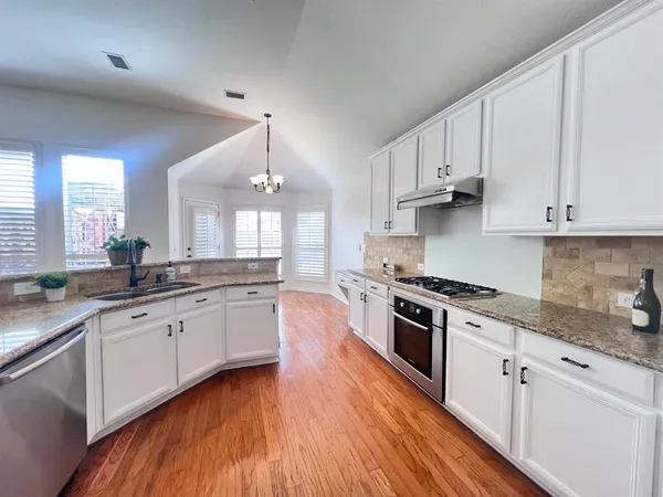 a view of a kitchen with kitchen island a sink wooden floor and a living room