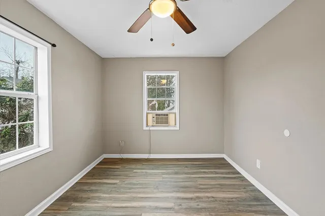 a view of empty room with wooden floor and fan