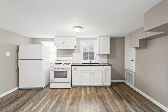 a kitchen with a refrigerator a stove top oven and a sink