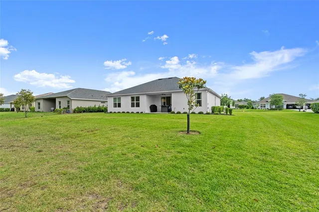 a white house with a big yard and large trees