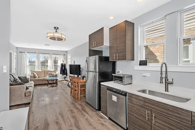 a kitchen with stainless steel appliances a stove top oven a sink dishwasher a refrigerator and cabinets with wooden floor