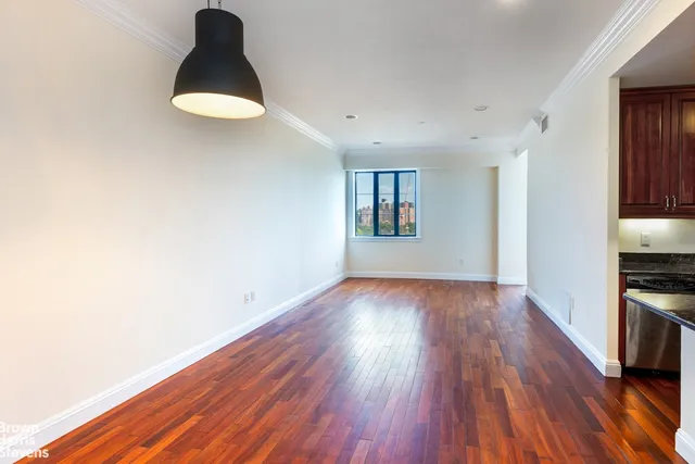 a view of a kitchen and an empty room with wooden floor