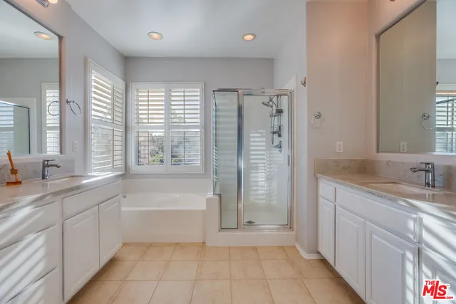 a bathroom with a granite countertop sink a large mirror a shower and a bathtub