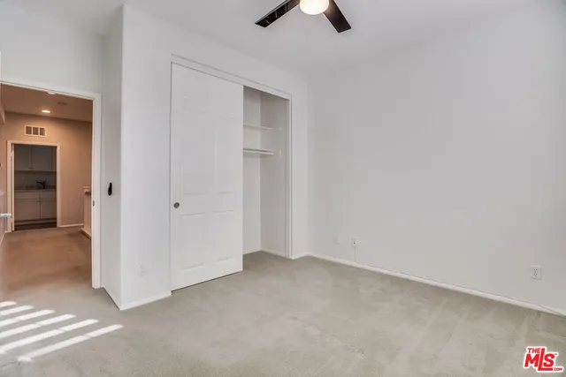 an empty room with ceiling fan and window