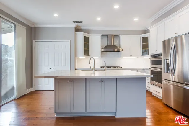a kitchen with stainless steel appliances granite countertop a refrigerator a sink and white cabinets