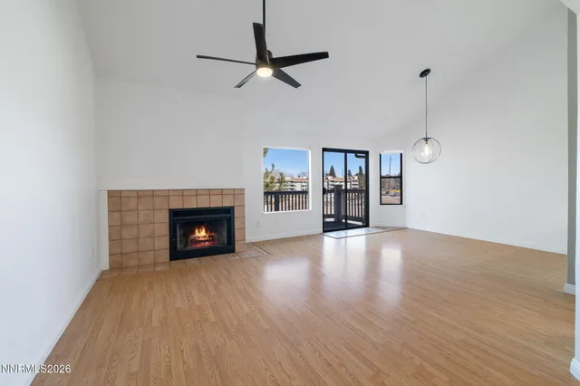 a view of an empty room with wooden floor fireplace and a window