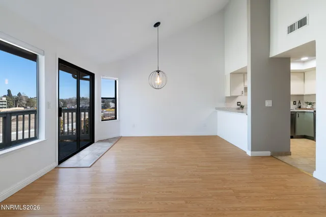 a view of an empty room with window and wooden floor