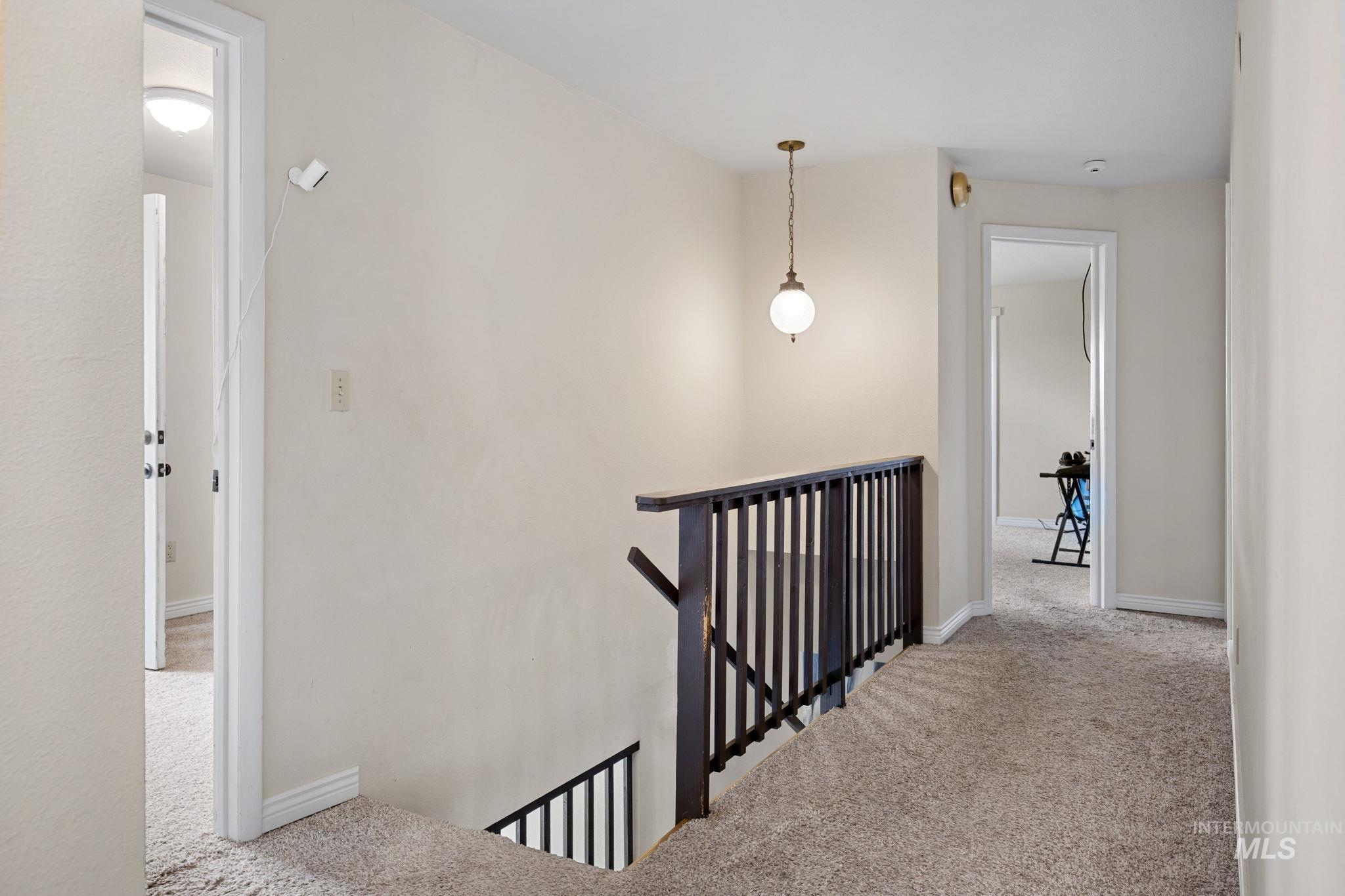 18338 Pride Lane Caldwell, ID 83607 - Photo 21 of 50 Carpeted hallway with a dark wood-finish railing and a brass pendant light fixture