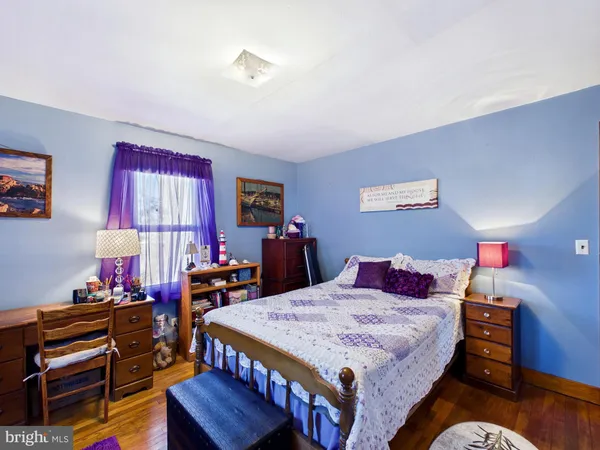 a bedroom with a bed a dresser and a chandelier