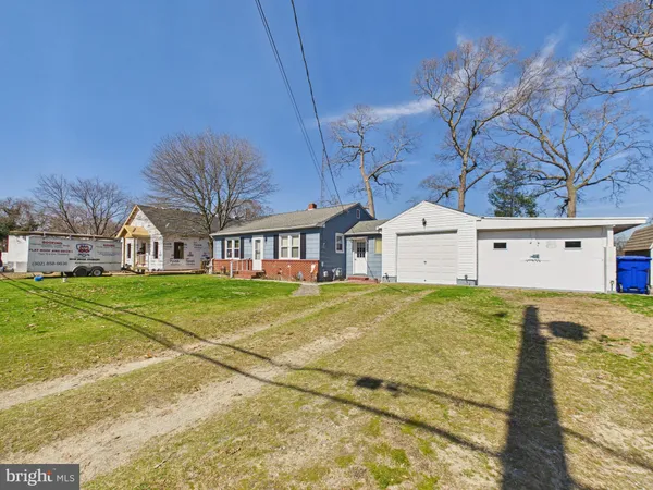 a view of a white house next to a yard with a big yard and potted plants