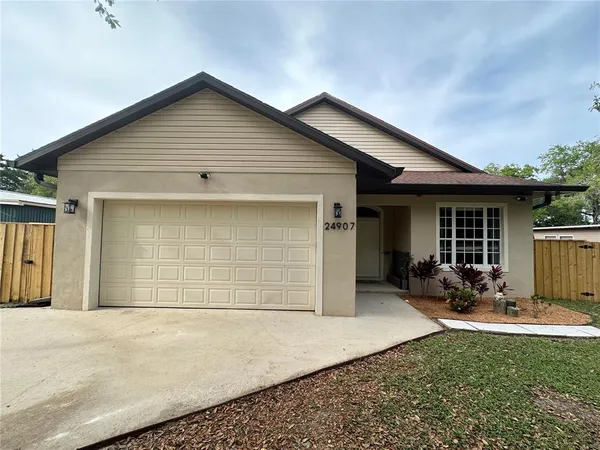 a view of a house with a large tree and a yard