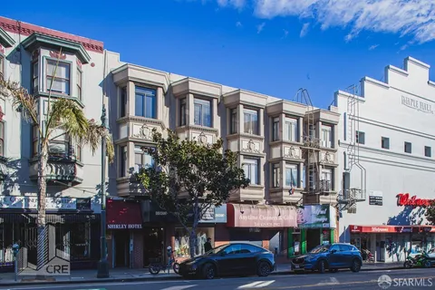 a front view of a building with lot of cars and trees