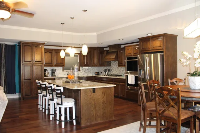 a kitchen with stainless steel appliances a dining table chairs and granite counter tops