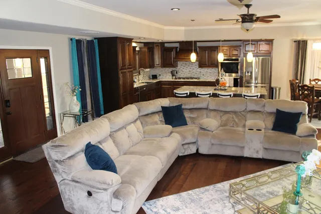 a living room with couches and kitchen view with wooden floor