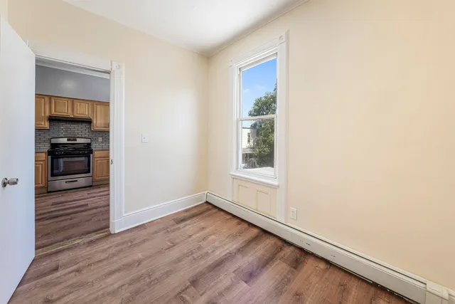 an empty room with wooden floor closet and windows