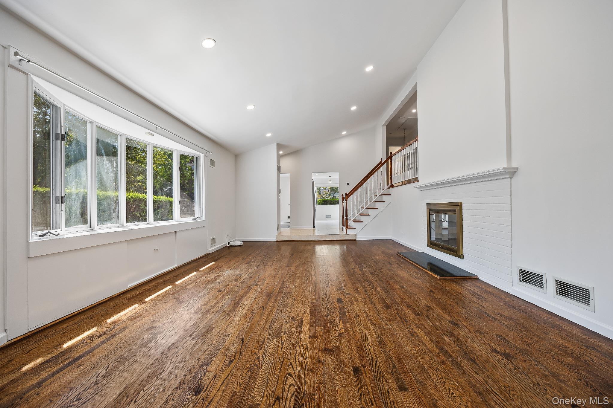 372 Heathcote Road Scarsdale, NY 10583 - Photo 9 of 20 Unfurnished living room featuring dark wood-style floors, recessed lighting, stairs, and high vaulted ceiling