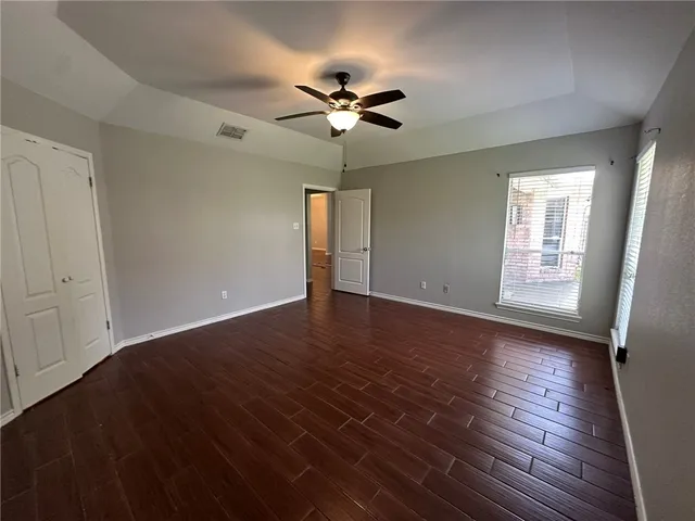 a view of empty room with wooden floor and fan