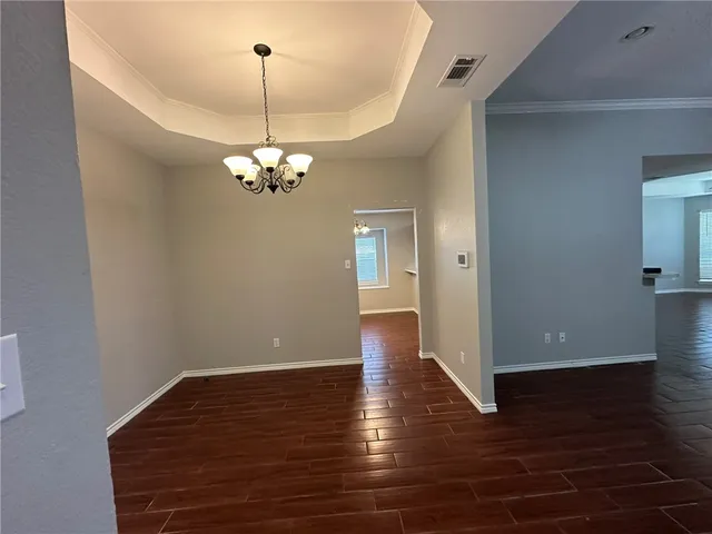 a view of a hallway with wooden floor and a chandelier
