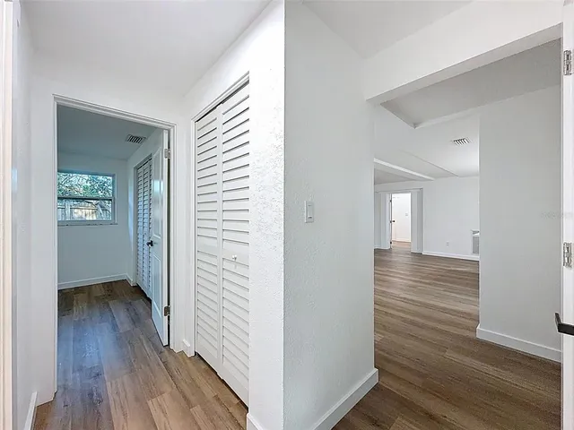 a view of a hallway with wooden floor and closet