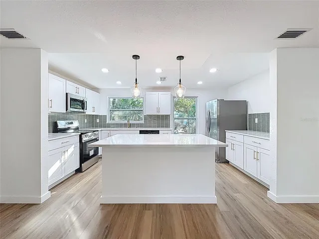 a large kitchen with cabinets wooden floor and stainless steel appliances