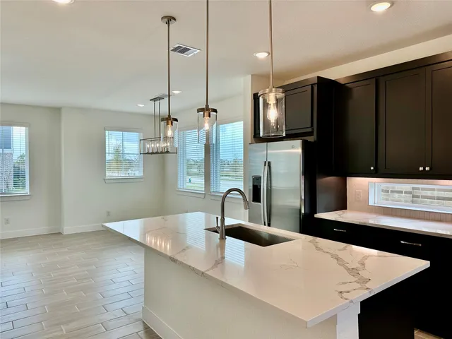 a kitchen with stainless steel appliances kitchen island granite countertop a sink a stove and a refrigerator