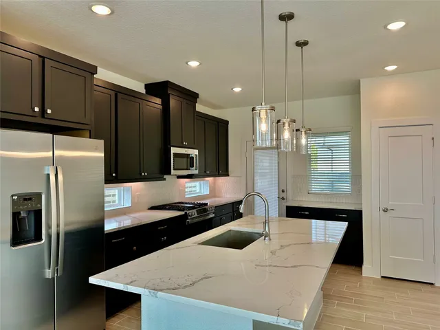 a large kitchen with a large counter top stainless steel appliances and cabinets