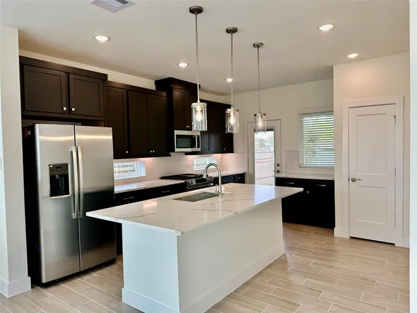 a kitchen with stainless steel appliances granite countertop a refrigerator a sink a stove and oven