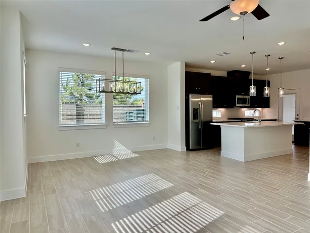 a open kitchen with stainless steel appliances granite countertop a refrigerator a sink dishwasher a stove and a dining table with wooden floor