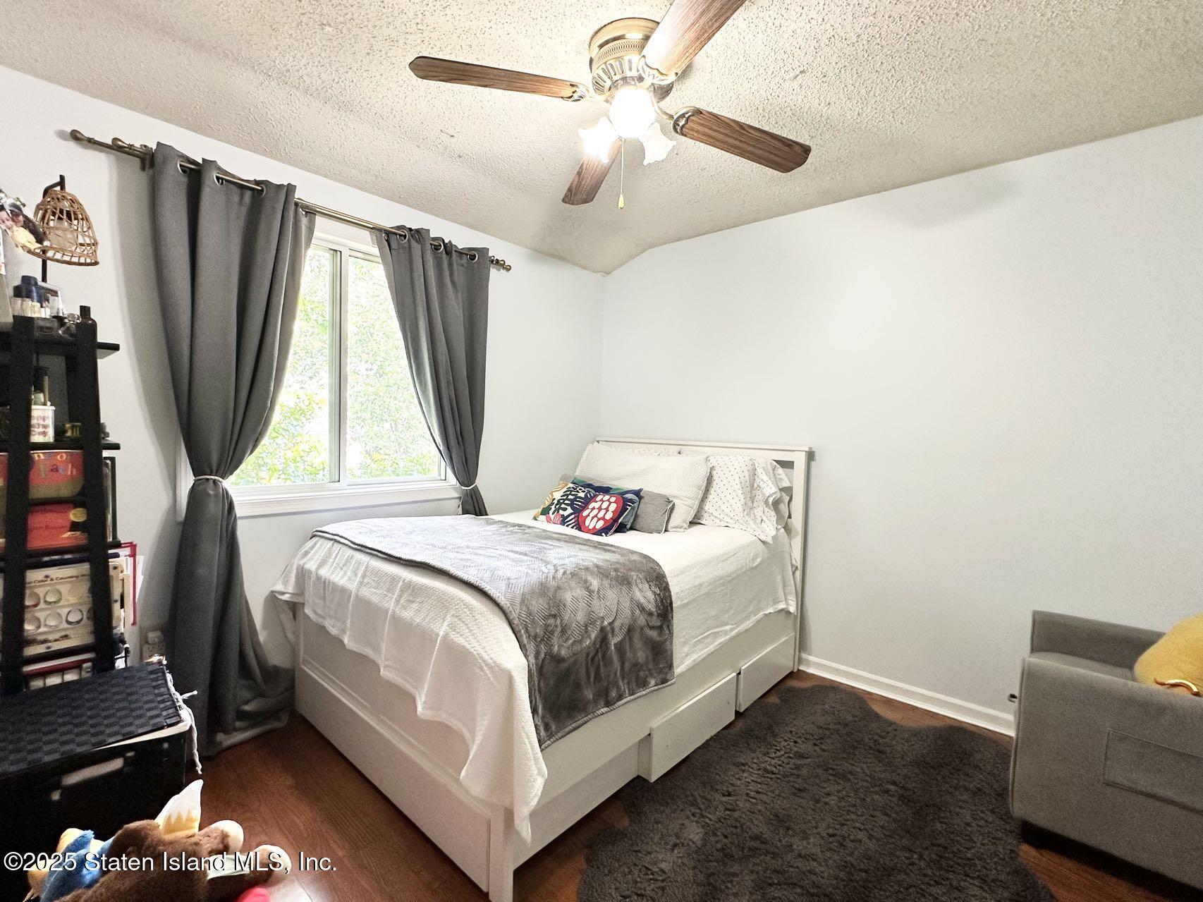 453 Ilyssa Way Staten Island, NY 10312 - Photo 9 of 16 a bedroom with a bed wooden floor and a flat screen tv