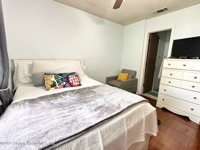 a bedroom with a bed and a flat tv screen on dresser