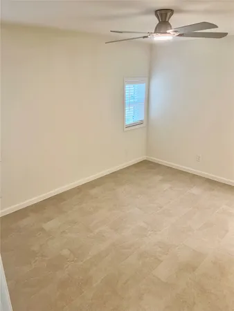 an empty room with a window and a fan