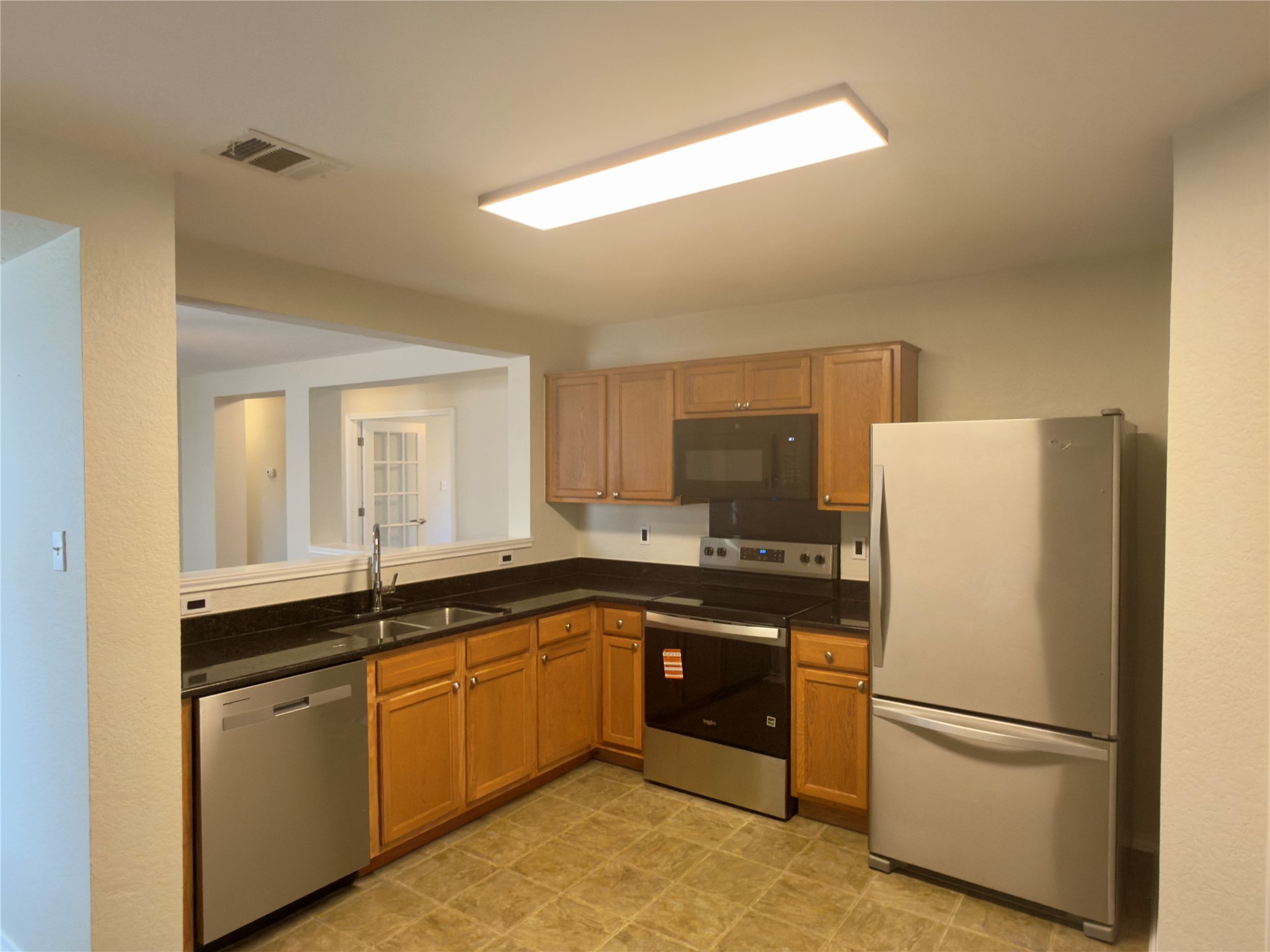 255 Myrtle Street Kyle, TX 78640 - Photo 4 of 31 Kitchen featuring wood cabinetry, stainless steel appliances, dark countertops, and tile flooring