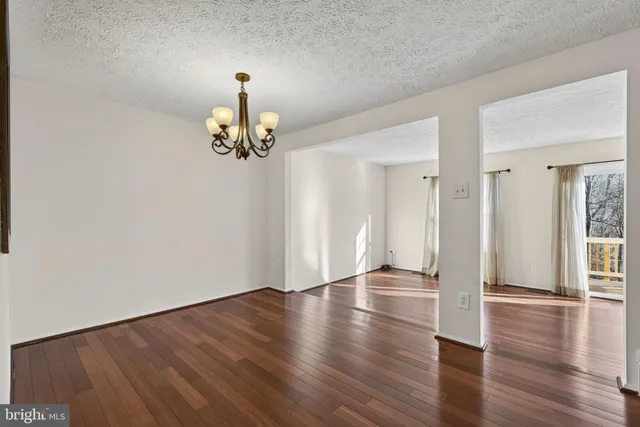 a view of a room with wooden floor staircase and a chandelier