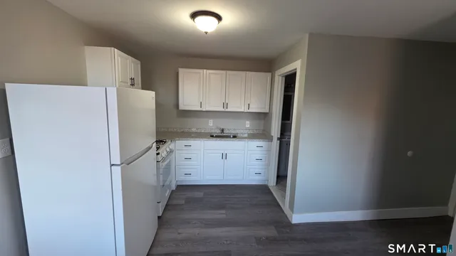 a kitchen with granite countertop white cabinets and white appliances