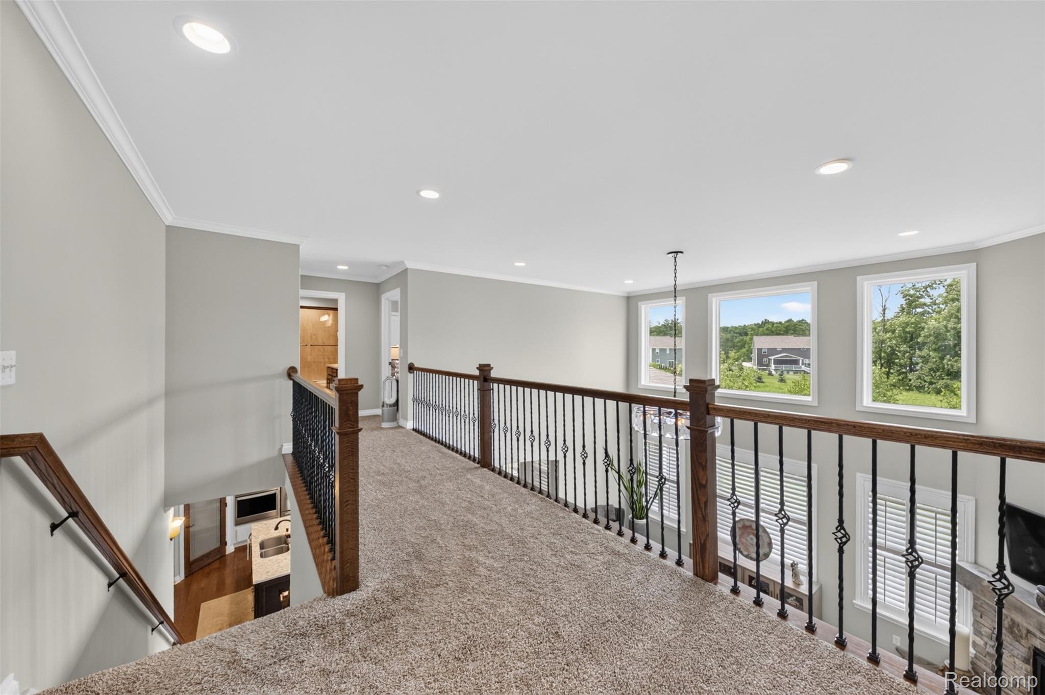 2531 Walnut View Drive Howell, MI 48855 - Photo 12 of 34 Carpeted loft featuring a wrought iron and wood railing overlooking the lower level, recessed lighting, crown molding, and three windows providing natural light