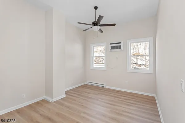 an empty room with wooden floor ceiling fan and windows