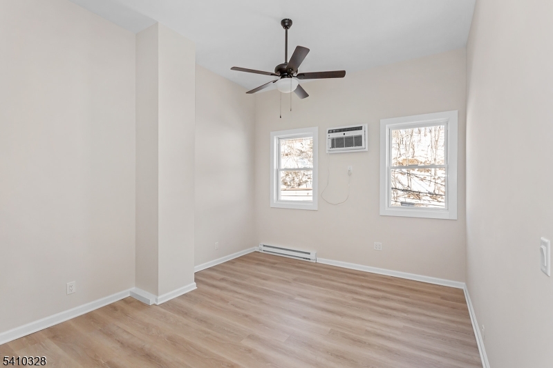 129 Main Street, Unit 3 Bloomingdale, NJ 07403 - Photo 5 of 21 an empty room with wooden floor ceiling fan and windows