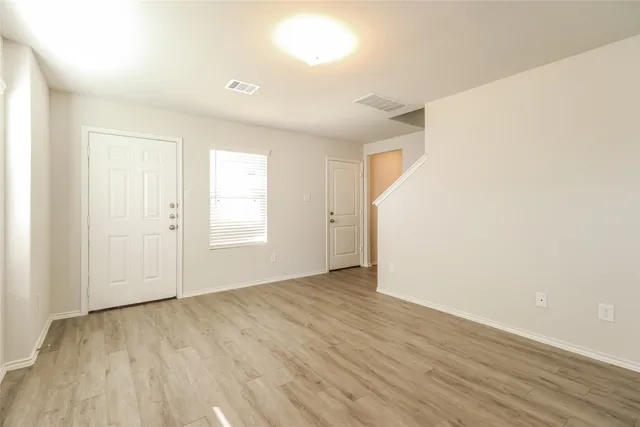 an empty room with wooden floor and windows