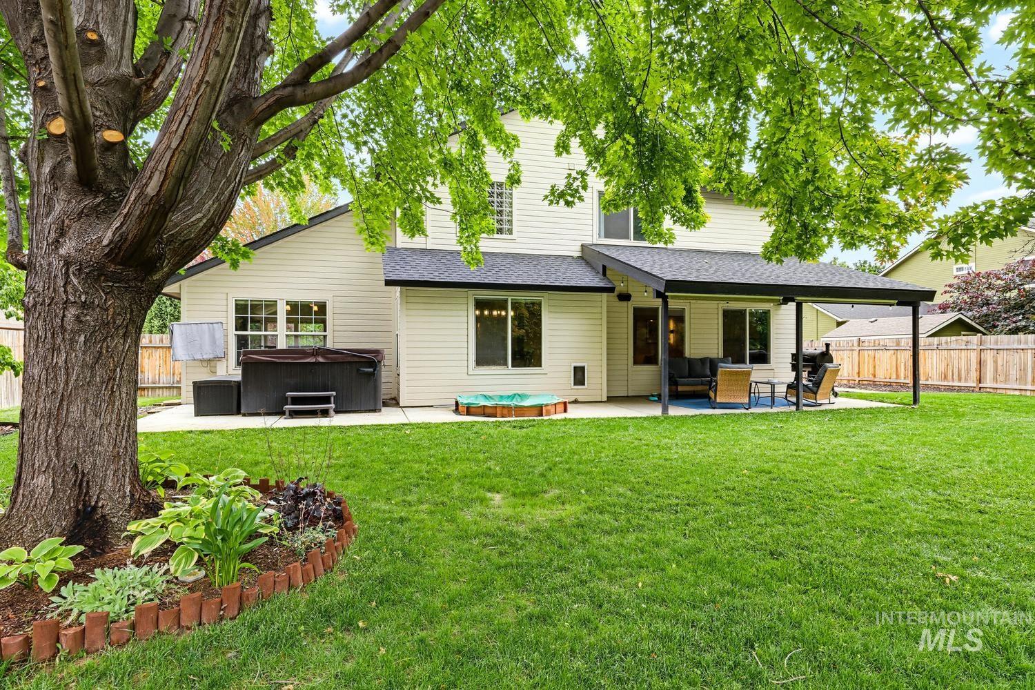 369 South Winthrop Way Boise, ID 83709 - Photo 42 of 50 Spacious backyard with a large concrete patio, covered outdoor living area, and extensive green lawn