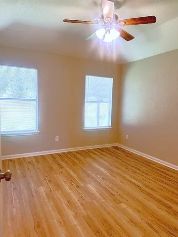 an empty room with windows and fan
