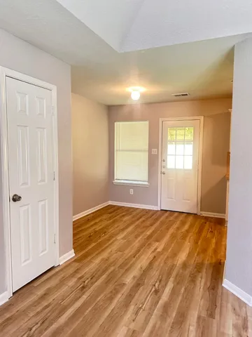 an empty room with wooden floor and windows
