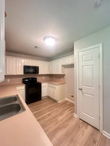 a kitchen with granite countertop a refrigerator and a stove top oven