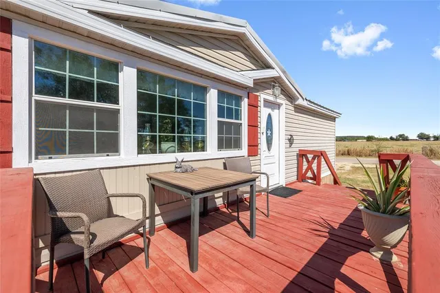 a balcony view with a dining table and chairs with wooden floor and fence