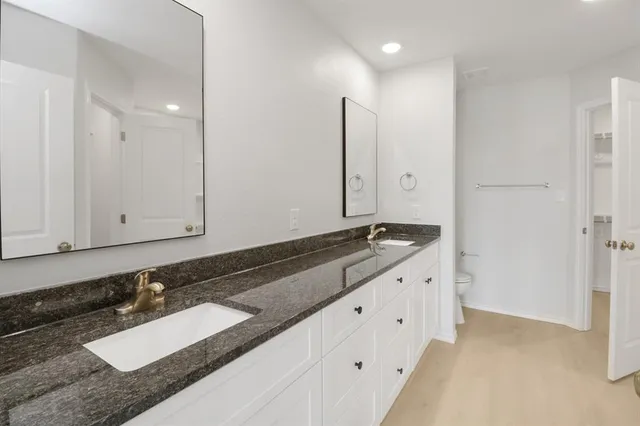 a spacious bathroom with a granite countertop sink a mirror and a bathtub
