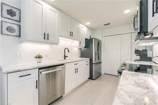 a kitchen with white cabinets and stainless steel appliances
