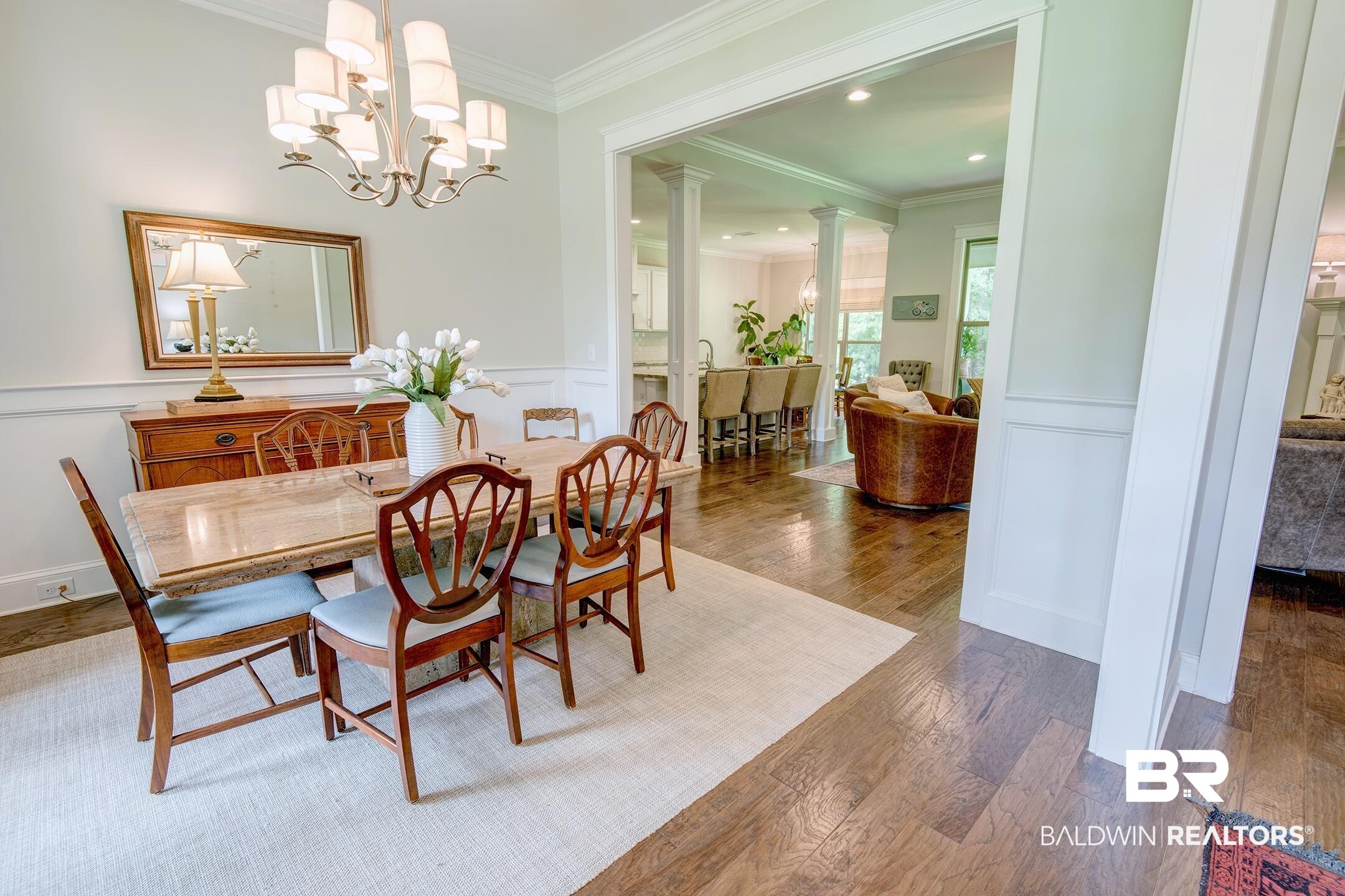 18754 Treasure Oaks Road Gulf Shores, AL 36542 - Photo 10 of 53 Dining area featuring wood-finish flooring, a multi-tier chandelier, crown molding, chair rail, and an open entryway to an additional living space
