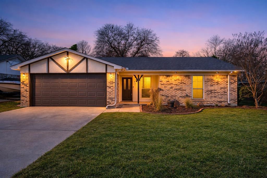 Ranch-style house featuring an attached garage, driveway, brick siding, and a front yard
